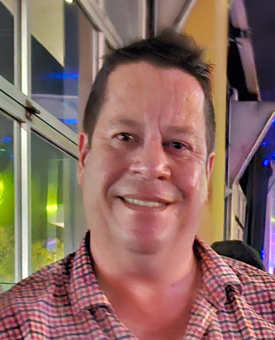 A portrait of a caucasian man with brown hair smiling at the camera.