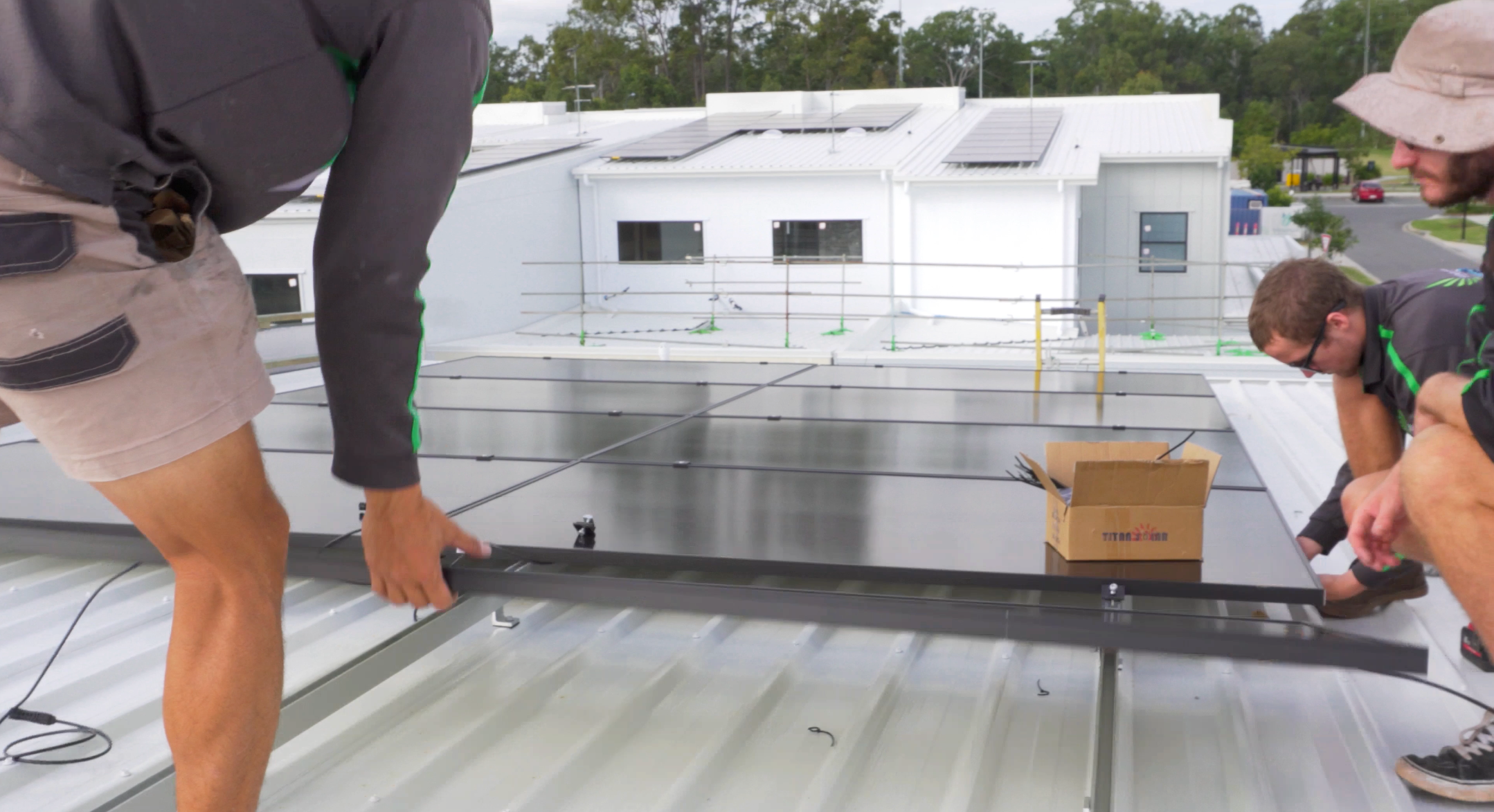 Two men (UV Power and Spark mate Electrical) installing a solar panel on a rooftop, harnessing renewable energy for sustainable power generation.