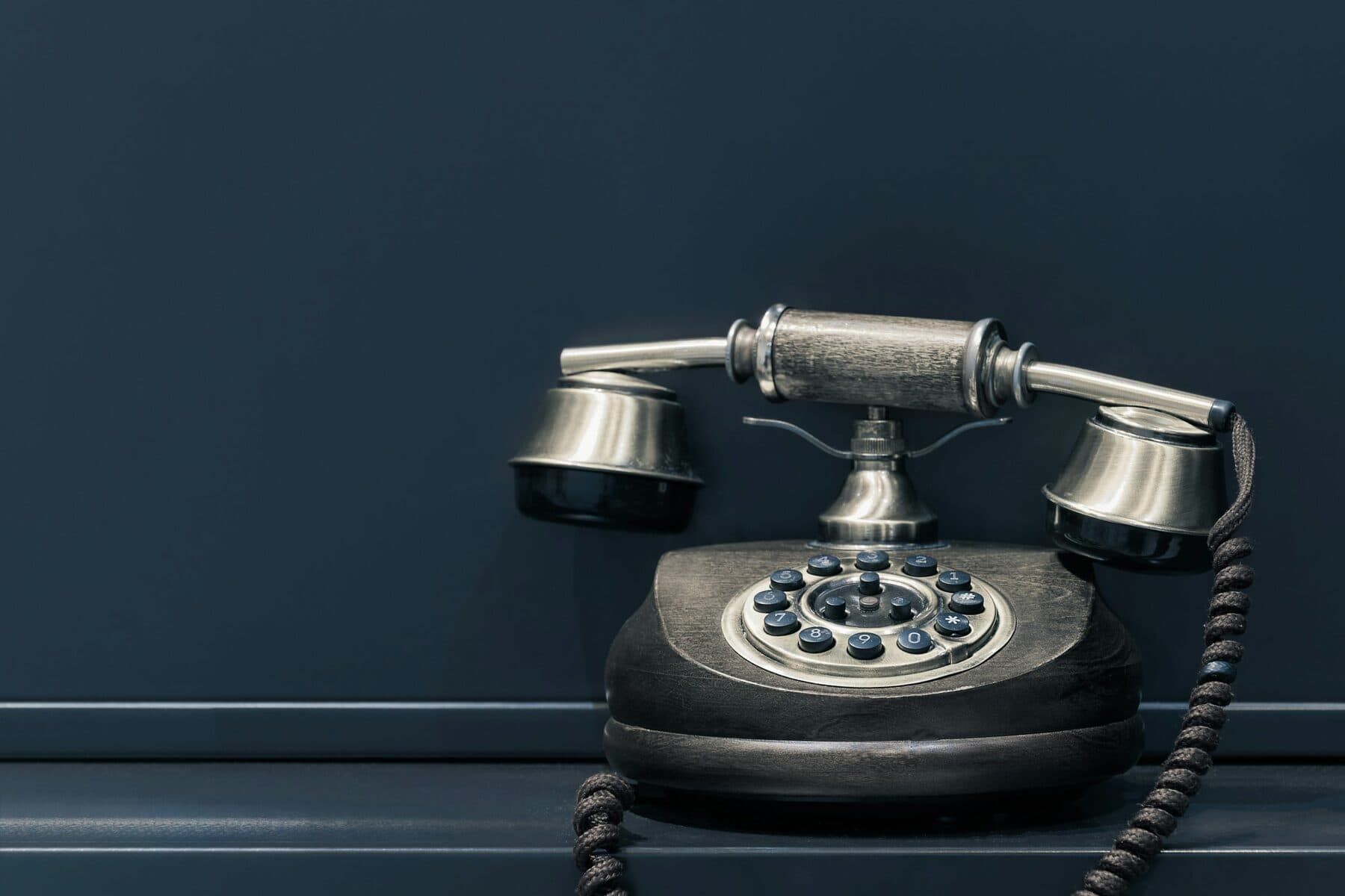 A classic telephone against a navy wall