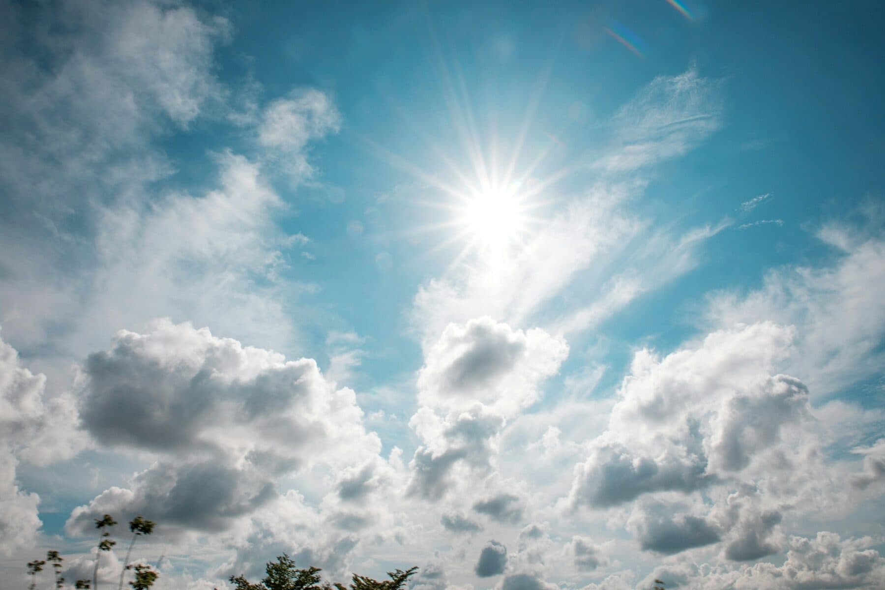 The sun in a blue sky with clouds
