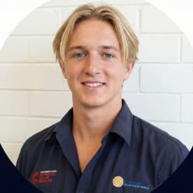 Zayn Pike, Chief Operating Officer at UV Power, smiling in a navy work shirt in front of a white brick wall