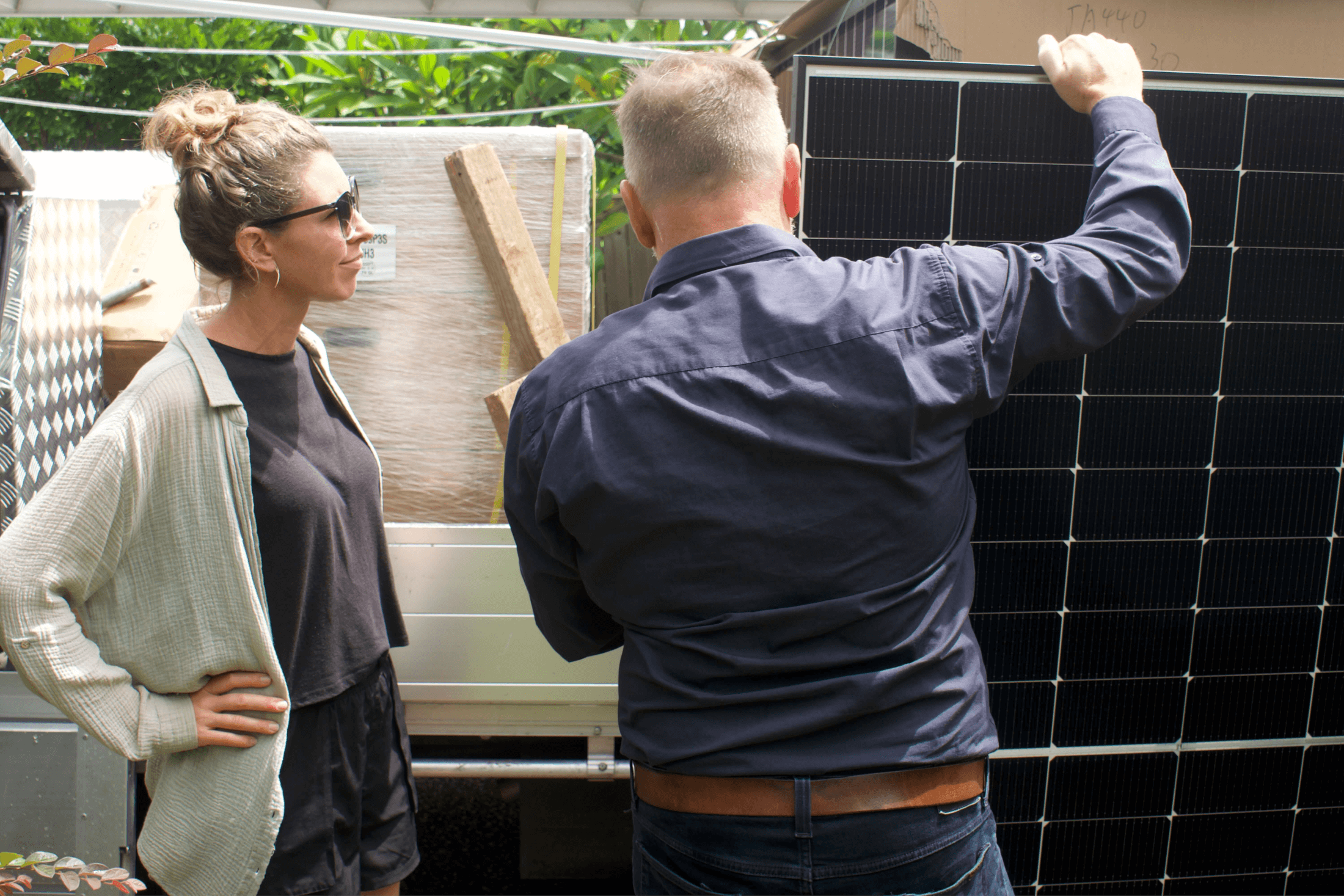 A solar installer and supplier in Brisbane showing a customer their new solar panels, unpacking them off the back of a ute.