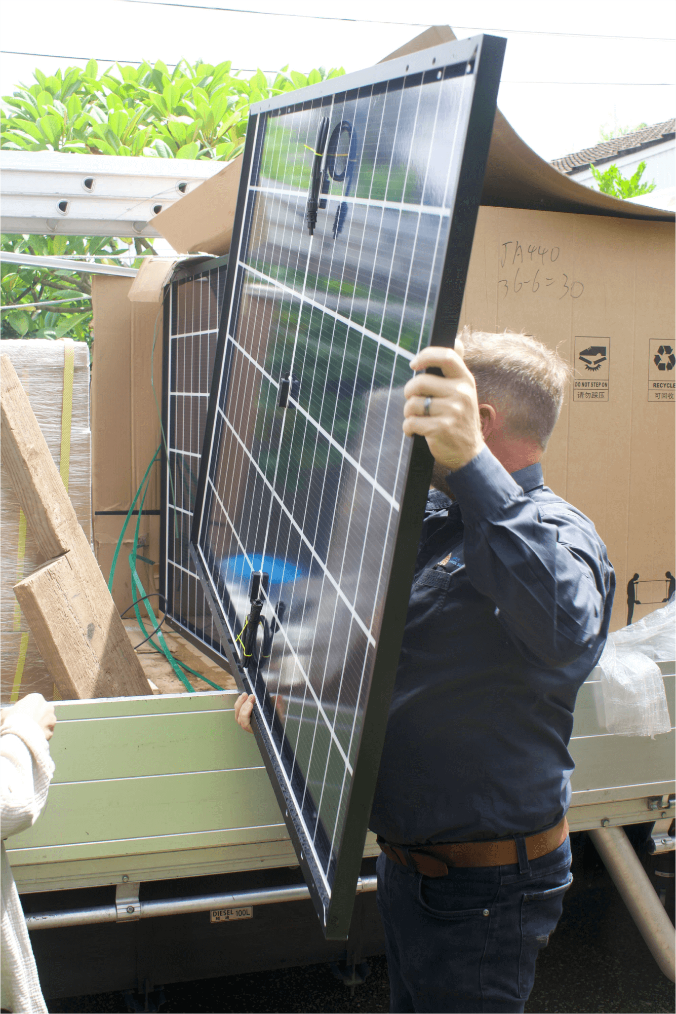 A solar installer and supplier unpacking solar panels from the back of a ute, and preparing them for installation for a customer in brisbane.